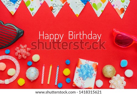 Happy birthday greeting card with gift box, glasses, beads, candle on red background