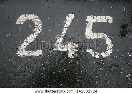 number painted in white on asphalt, white parking numbers 245
