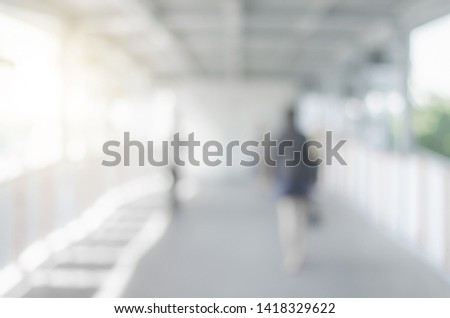 blur background image of empty modern sky walk way in city with people walking indoor and sunlight abstract gray blur bokeh.