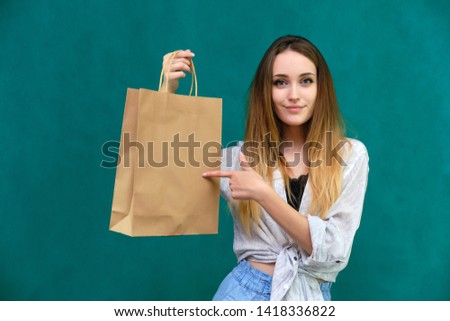 Photo of a portrait of a beautiful girl woman with long dark flowing hair, loves shopping, on a green background with packages. She is standing in different poses and smiling. Made in studio