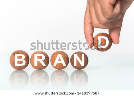Hand putting on Wooden ball with word "BRAND" concept