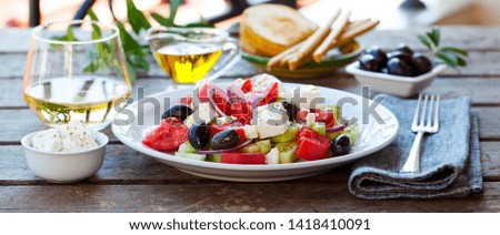 Greek salad. Fresh vegetables, feta cheese and black olives with white wine. Outdoor background.