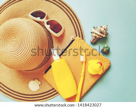 Sun hat, sunglasses, cosmetic bag, sunscreen bottle, toothbrush, seashells and rubber duck. Flat lay summer travel photo, beach essentials