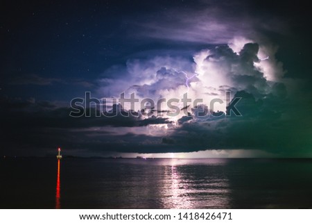 storm clouds with lightning against the starry sky over the sea and the lighthouse