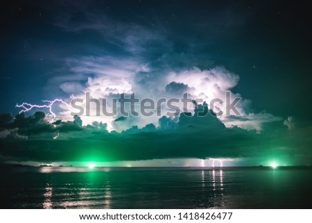 storm clouds with lightning against the starry sky over the sea and the lighthouse