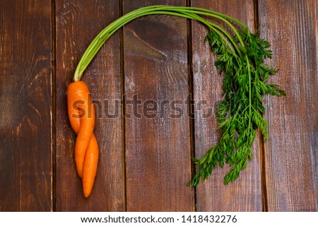 Ugly organic carrot on wooden background. Image with copy space, top view. Royalty-Free Stock Photo #1418432276