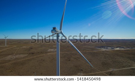 Aerial photo near the wind turbine located in meadows that also shows more windmills powered by aerofoil that provide sustainable energy.