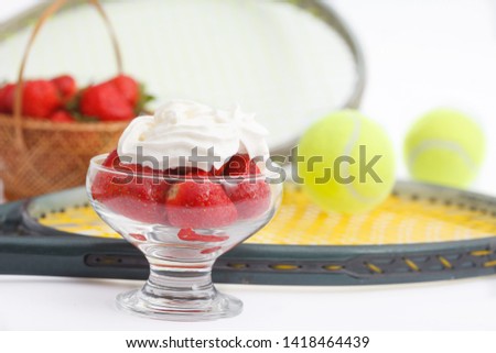 Strawberries with whipped cream and  tennis equipment on Wimbledon tournament. Wimbledon Grand slam celebration concept. Close up image.