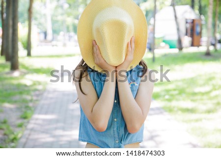 Trend without face, portrait of a girl covering her face with a hat posing in the Park in the summer. summer vacation.