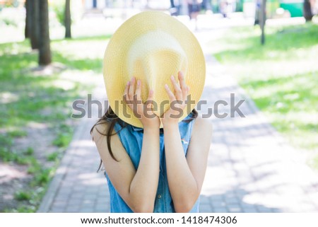 portrait of a girl covering her face with a hat posing in the Park in the summer. summer vacation.