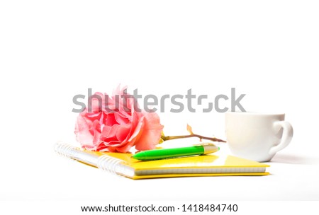 yellow notebook rose and pen on a white background