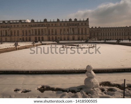 garden sculptures and pond in front of the royal residence at Versailles near Paris in France in winter scenery, the snow