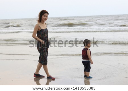 mom and son walking on the beach 