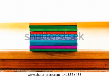 Several books stacked by their backs of different colors like rainbow, empty to fill with text.