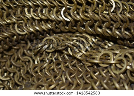 A closeup, macro photo of gold coloured chain mail. 