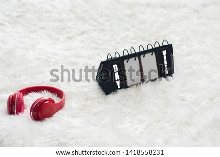 Red headphones and metal calendars,are placed on a white carpet with the concept of Music Day and relaxation from stress.