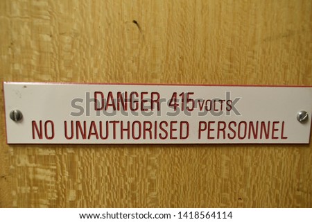 Photograph of a Danger 415 volts no unauthorised personnel, sign on a wooden door. 