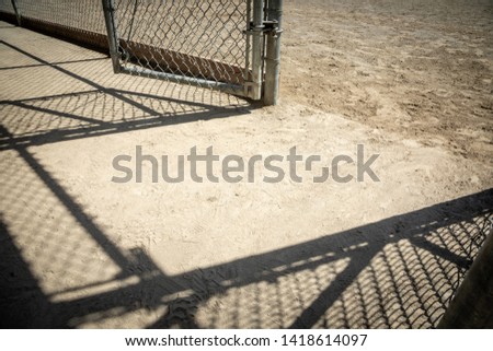 Close up on the dusty concrete floor of a baseball dugout, with dramatic chainlink fence shadows, in an abstract sports background