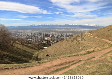 Hikers walk on the trails in the Wasatch Mountain foothills near Salt Lake City with the snowcapped Oquirrh mountains in the background in early spring