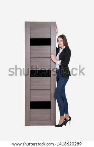 Beautiful woman peeking from behind the white door, isolated on white background with copy space