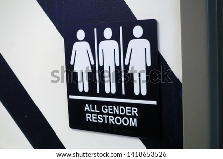 A all gender bathroom sign on a wall outside of a restroom.