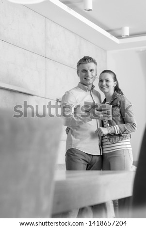 Black and White photo of Portrait of smiling couple holding digital tablet while standing in apartment