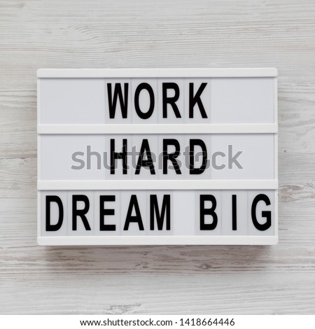 Light box with 'Work hard dream big' words on a white wooden background, top view. Flat lay, overhead, from above. Close-up.