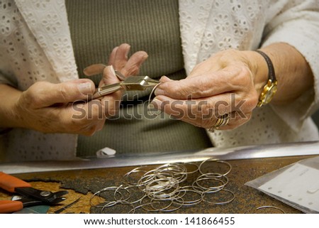 A close up on a jeweler's hands while working making jewelry. Royalty-Free Stock Photo #141866455