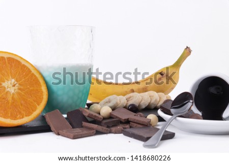 Melted Chocolate In A Cup, spoon, a half of orange and banana Isolated On White background
