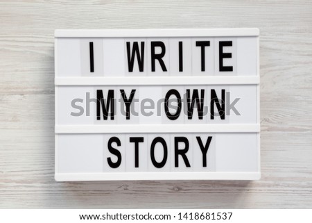 'I write my own story' words on a modern board on a white wooden background, top view. From above, overhead, flat lay. Close-up.