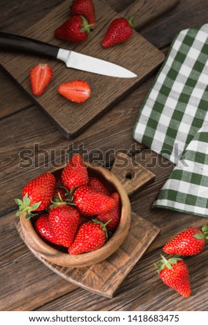 Strawberries in a wooden bowl on a wooden background. Rustic style. Top view with space for text