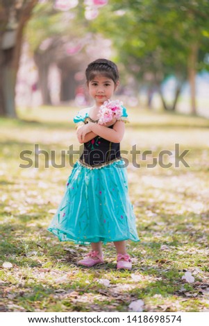 Portrait of cute smiling three year old girl in princess dress holding spring flowers