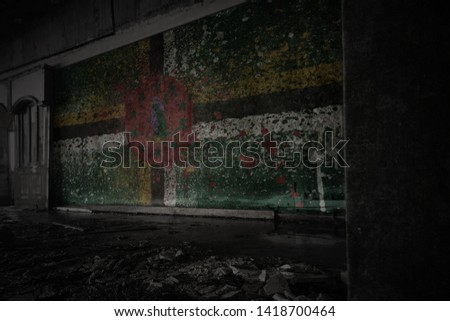 painted flag of dominica on the dirty old wall in an abandoned ruined house. concept