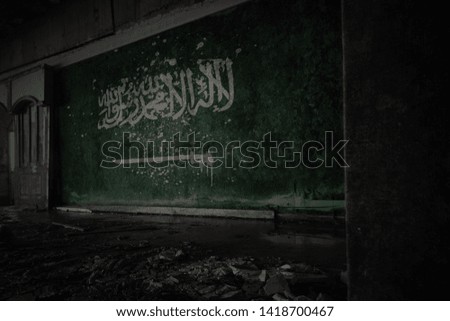 painted flag of saudi arabia on the dirty old wall in an abandoned ruined house. concept