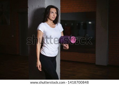 Sporty attractive woman holding yoga mat before or after fitness class, active girl ready for yoga and sport exercise to enjoy healthy sporty hobby, indoor body close up