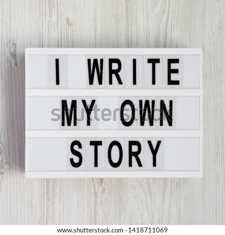 'I write my own story' words on a modern board on a white wooden surface. From above, overhead, flat lay, top view.