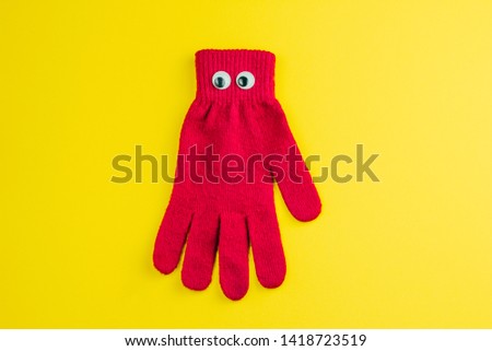 top view red  glove  with googly eyes isolated  on a yellow background
