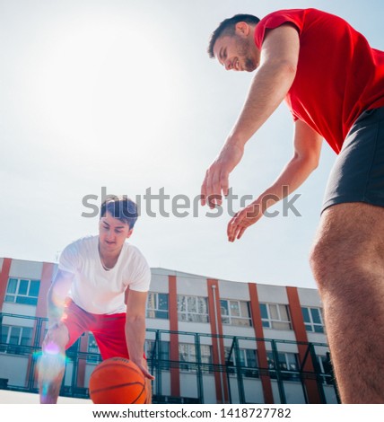 Two Caucasian basketball player fighting for ball possession at the basketball court on a sunny day, shot against the sun, contrjeur