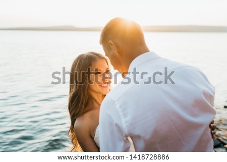 A happy newly married couple posing by the water