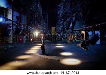 A young guy mounts lighting equipment on the stage of the theater Royalty-Free Stock Photo #1418740013
