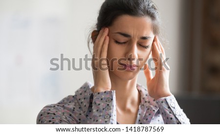 Close up indian ethnicity millennial female portrait closed eyes touch temples feels unhealthy suffers from throbbing pain migraine, tension headaches caused by overworking and stressful work concept Royalty-Free Stock Photo #1418787569