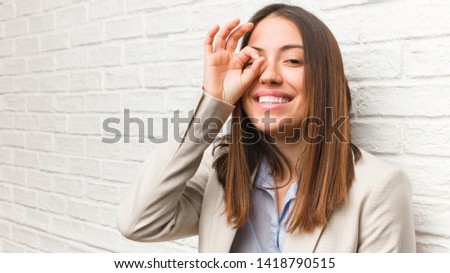 Young business woman confident doing ok gesture on eye