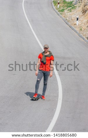 Tall fit male riding a longboard on an open road while performing a speed tuck.