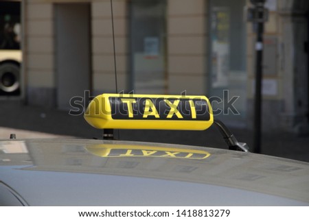 a sign "TAXI" on a car roof