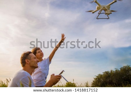 Young father shows his cute daughter how to control drone outdoors.