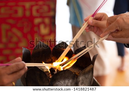 hands light the incense sticks in temple