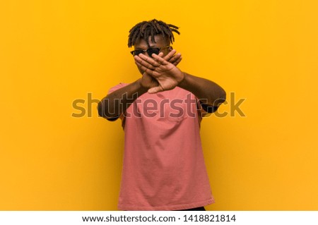 Young casual black man wearing sunglasses doing a denial gesture