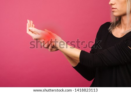 Female holding hand to spot of wrist pain. Concept photo with Color Enhanced skin with read spot indicating location of the pain.