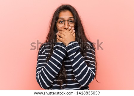 Young intellectual indian woman shocked covering mouth with hands.