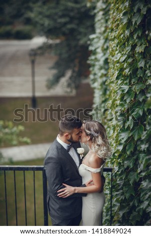 Beautiful bride in a long white dress. Handsome groom in a black suit. Couple in a summer park